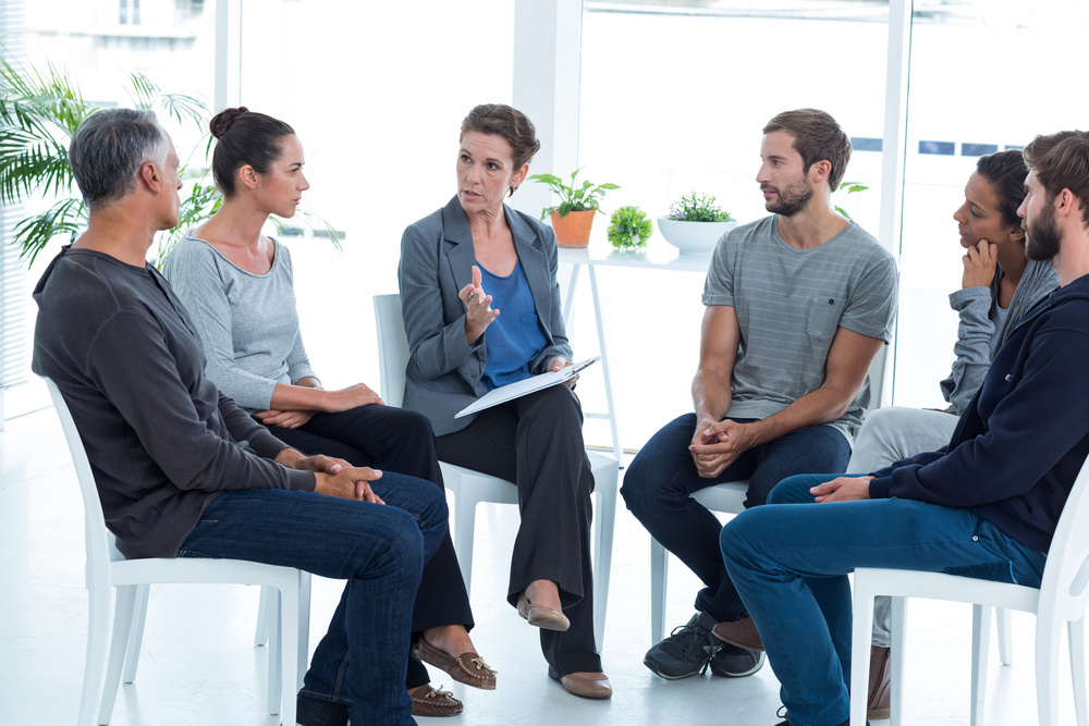 Group therapy in session sitting in a circle in a bright room-1